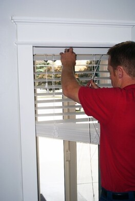 Man Rehanging Clean Blinds